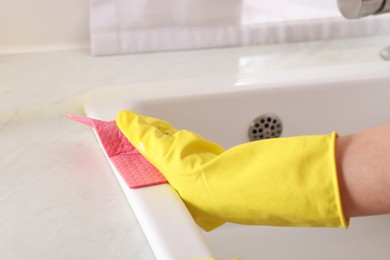 Photo of Woman cleaning sink with rag in kitchen, closeup