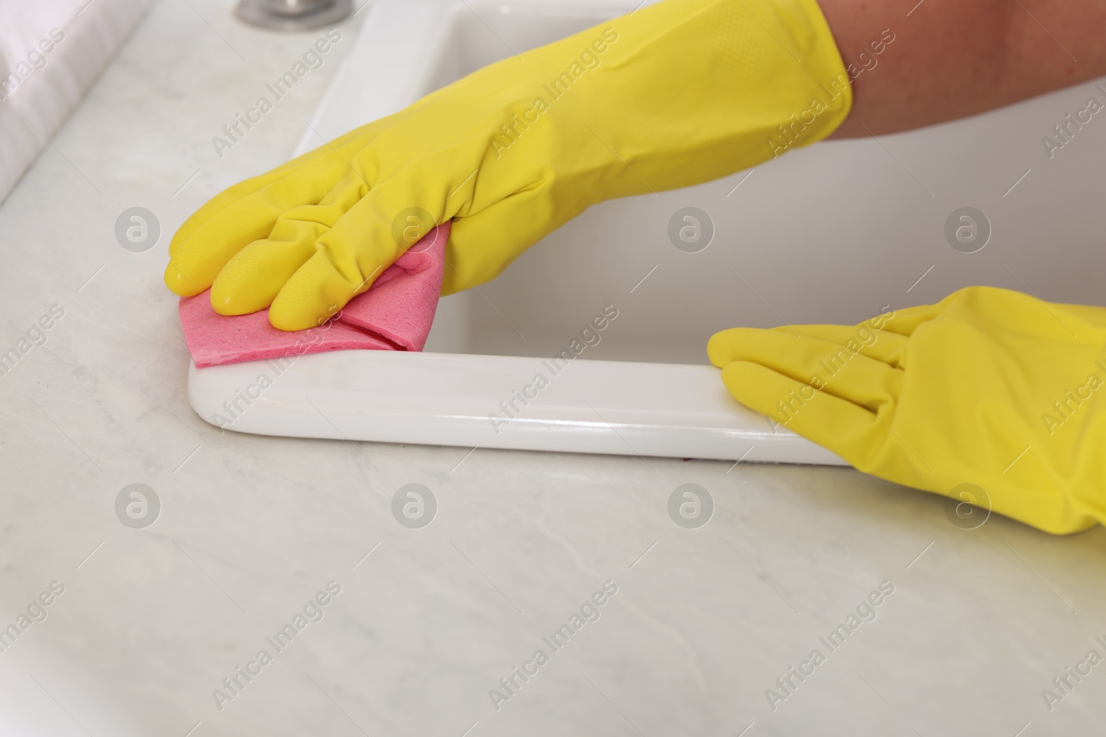 Photo of Woman cleaning sink with rag in kitchen, closeup