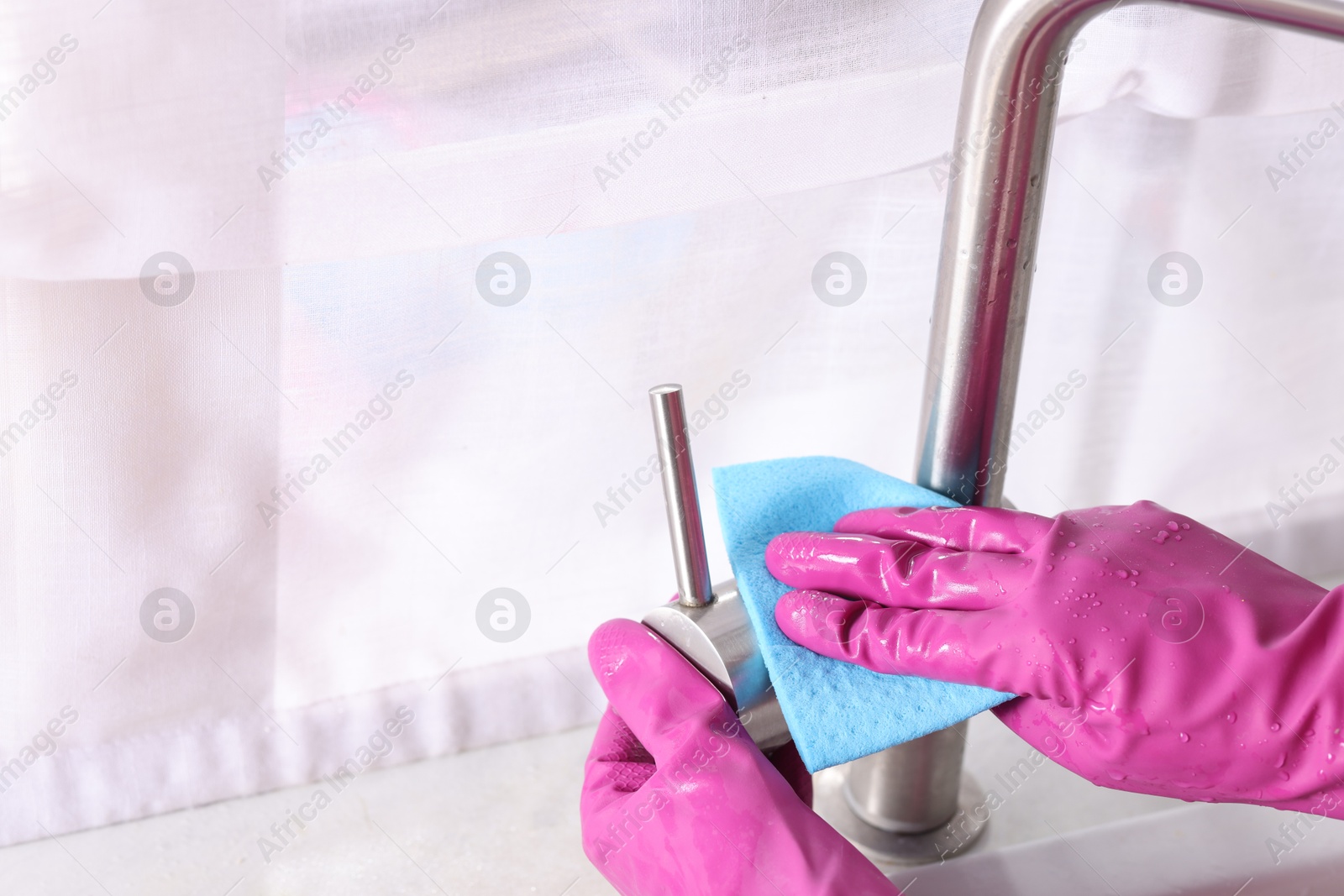 Photo of Woman cleaning faucet of kitchen sink with rag indoors, closeup. Space for text