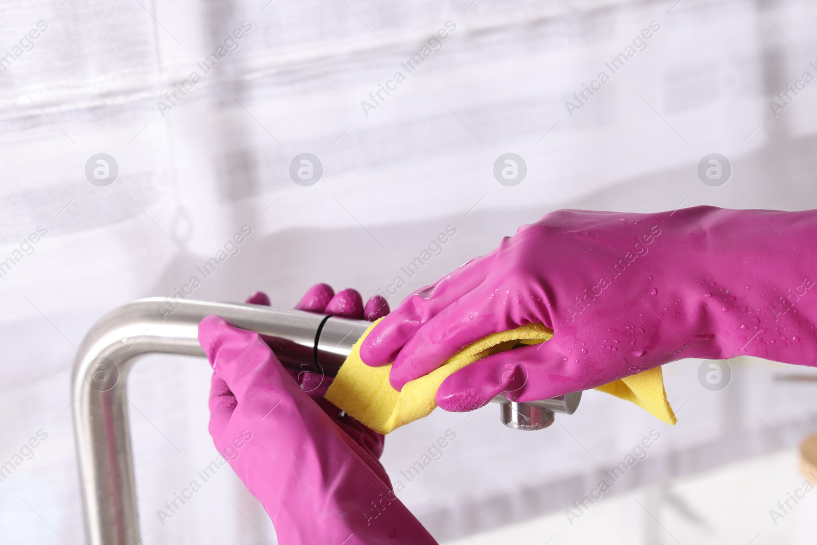 Photo of Woman cleaning faucet of kitchen sink with rag indoors, closeup