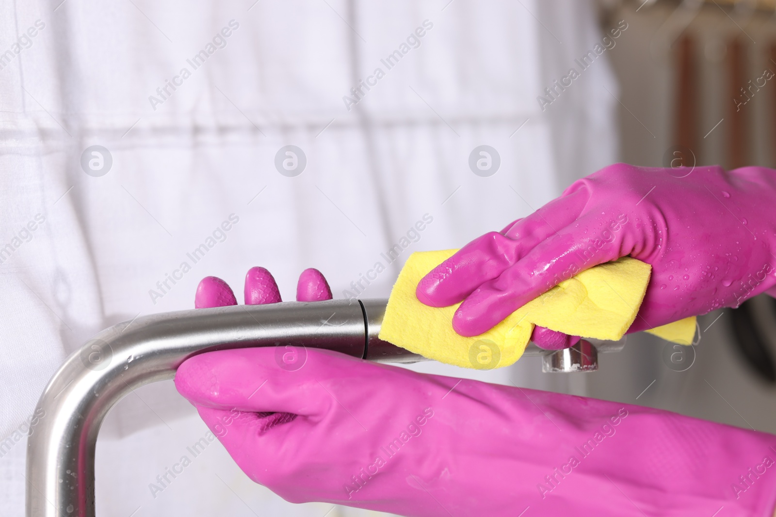 Photo of Woman cleaning faucet of kitchen sink with rag indoors, closeup