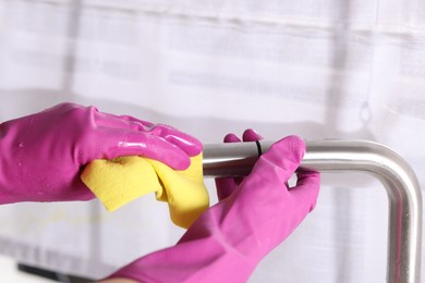 Photo of Woman cleaning faucet of kitchen sink with rag indoors, closeup