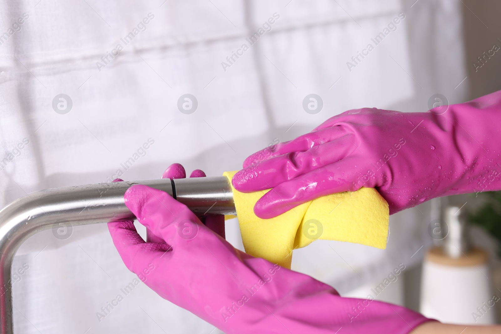 Photo of Woman cleaning faucet of kitchen sink with rag indoors, closeup