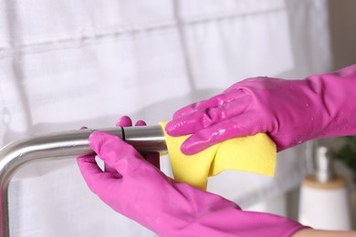 Photo of Woman cleaning faucet of kitchen sink with rag indoors, closeup