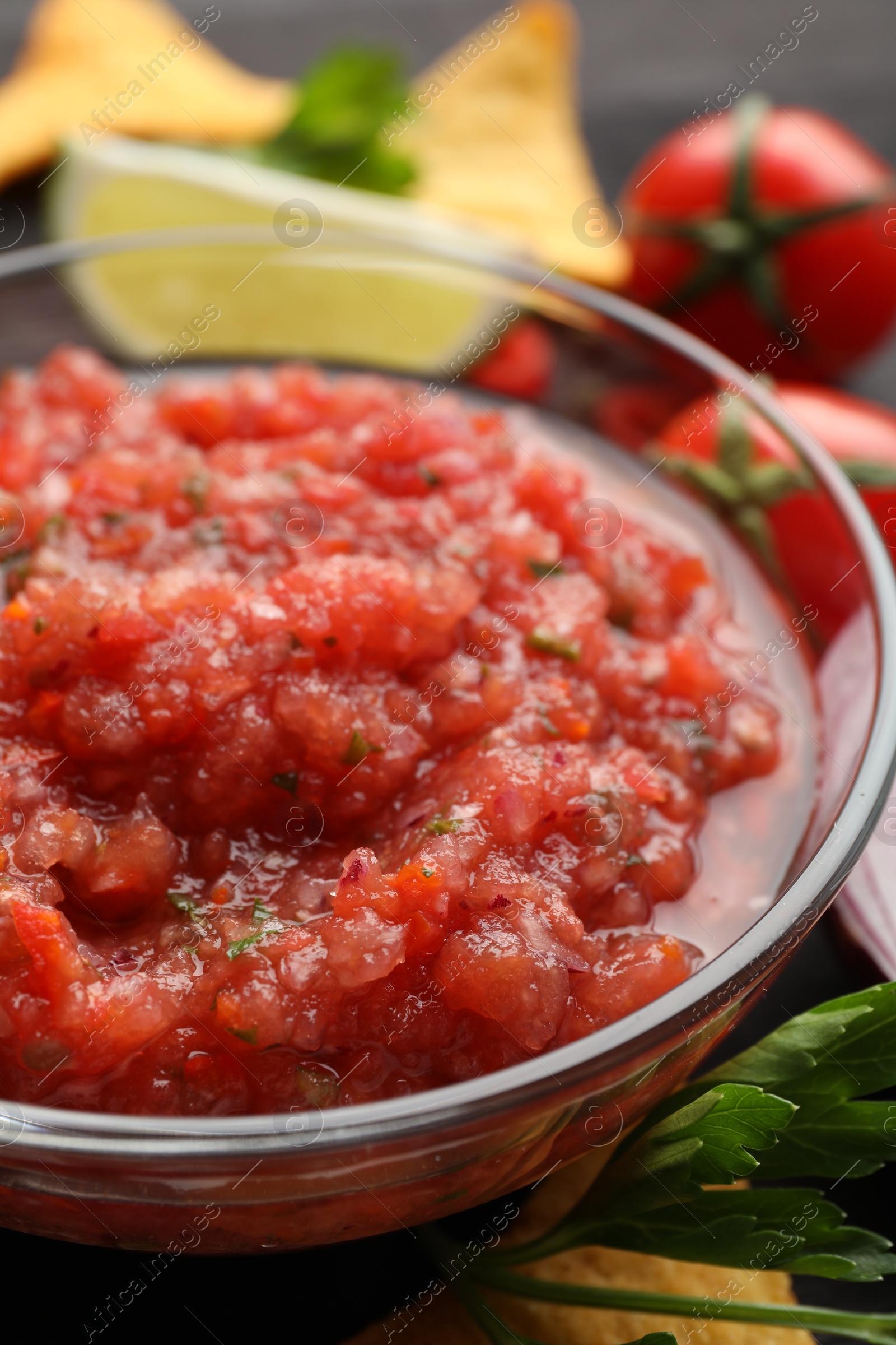 Photo of Spicy salsa in bowl and ingredients on table, closeup