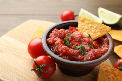 Photo of Spicy salsa in bowl, nachos and tomatoes on table, closeup. Space for text