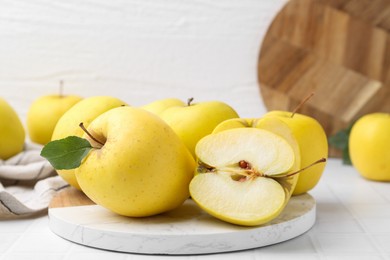 Fresh ripe yellow apples on white tiled table, closeup