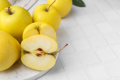 Photo of Fresh ripe yellow apples on white tiled table, closeup. Space for text