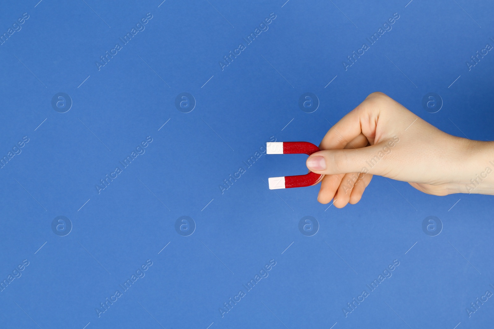 Photo of Woman with horseshoe magnet on blue background, closeup. Space for text