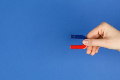 Photo of Woman with horseshoe magnet on blue background, closeup. Space for text