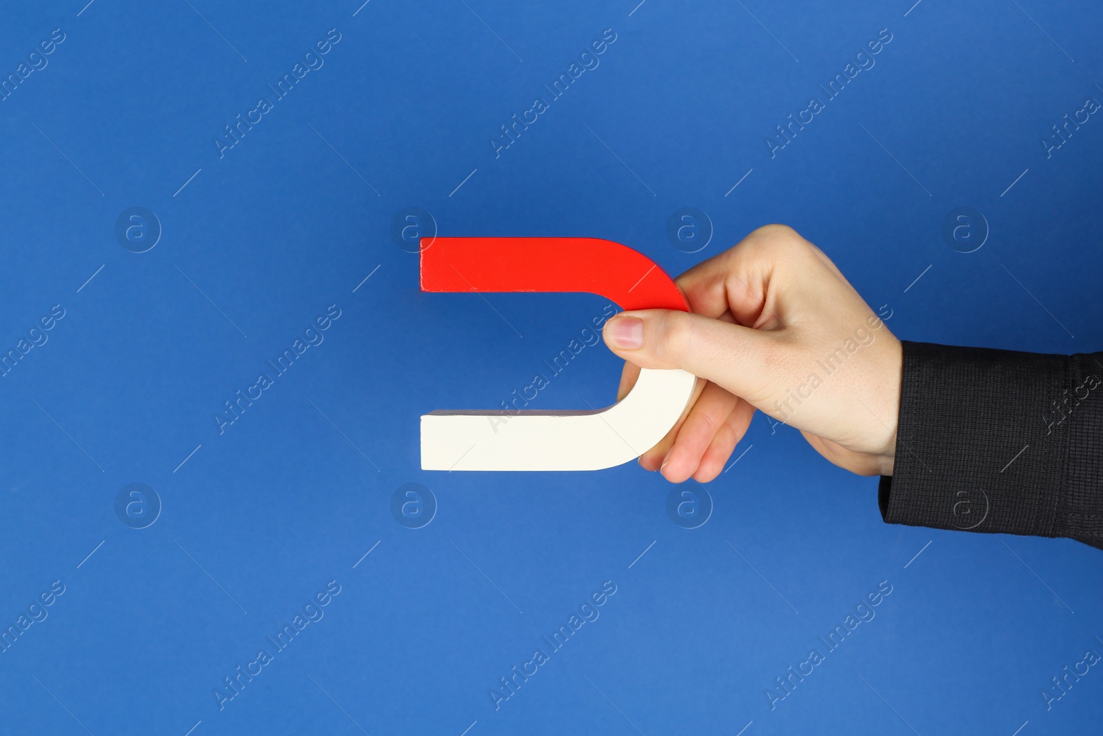 Photo of Woman with horseshoe magnet on blue background, closeup