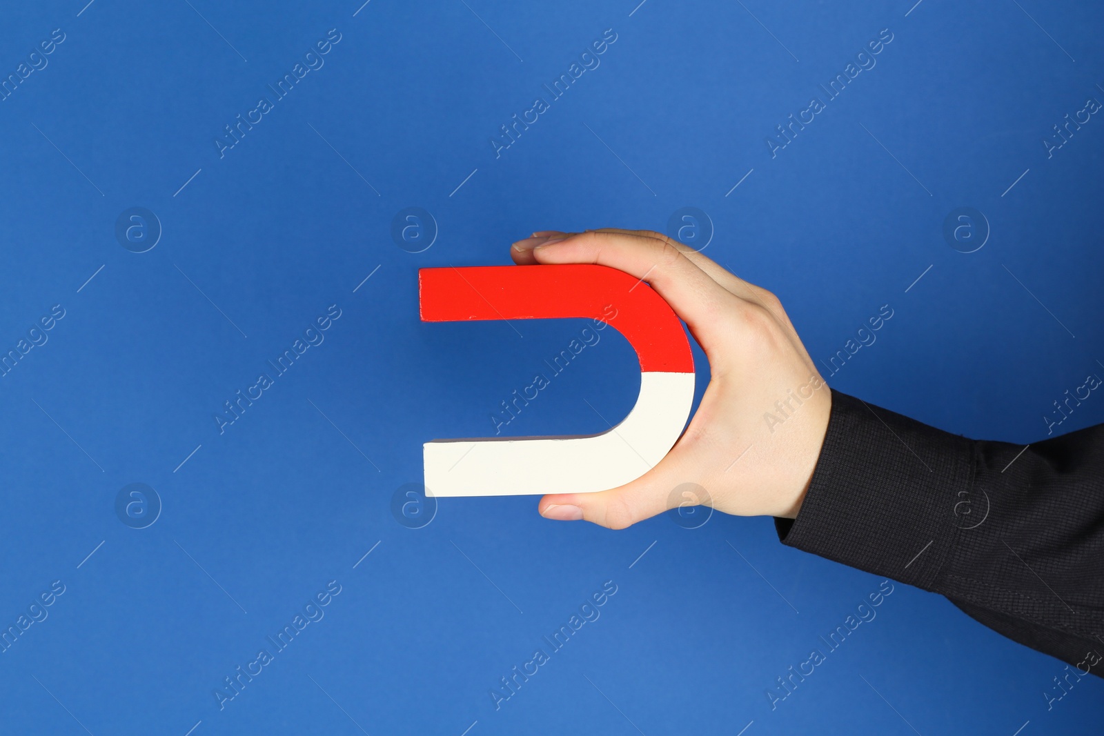 Photo of Woman with horseshoe magnet on blue background, closeup