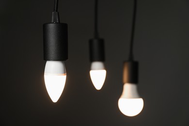 Photo of Light bulbs hanging on cords against grey background, selective focus. Space for text