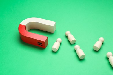 Photo of Magnet attracting human figures on green background