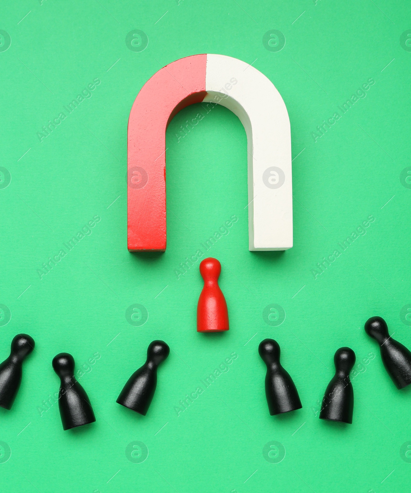 Photo of Magnet attracting human figures on green background, flat lay