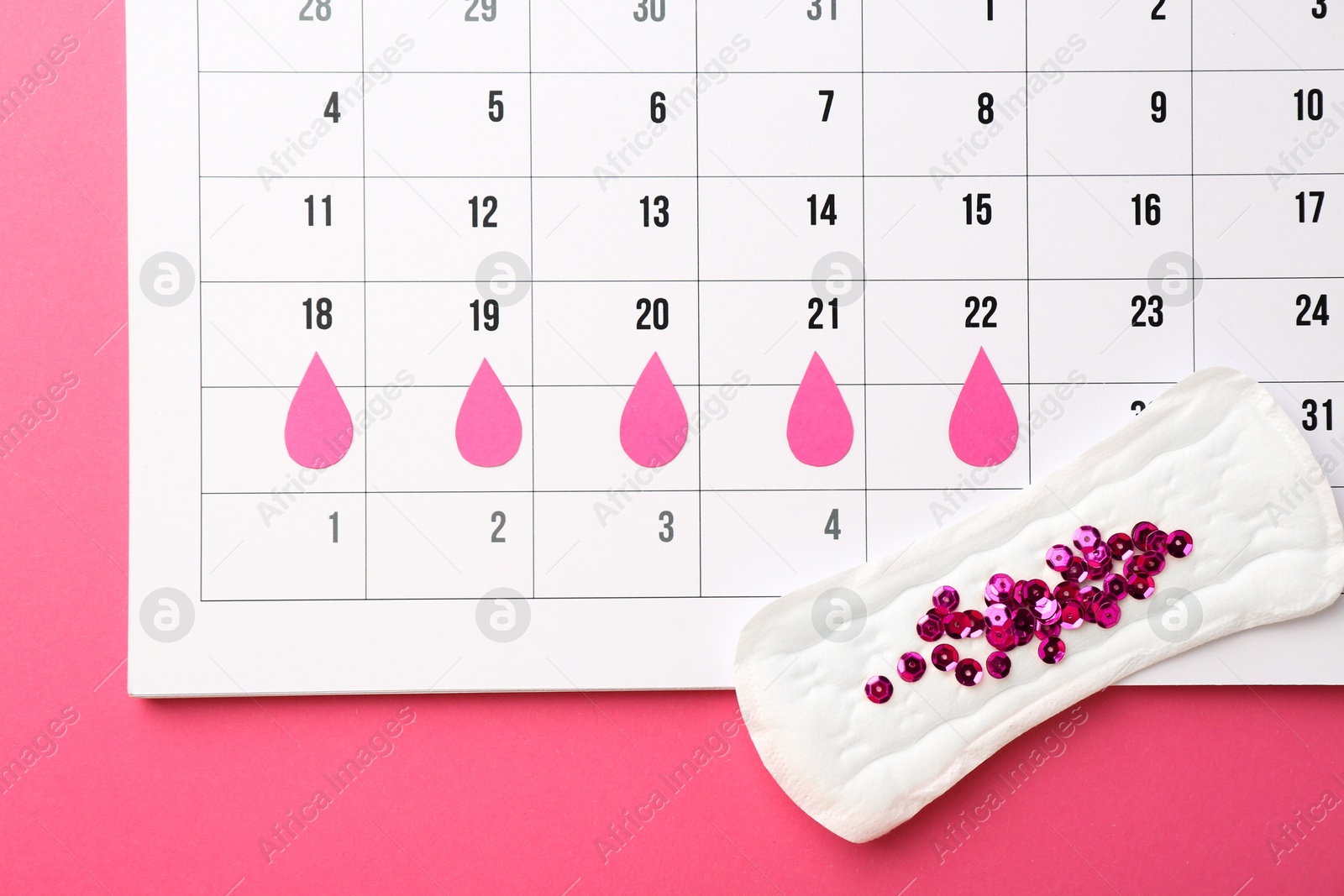 Photo of Calendar with marked dates and menstrual pad with sequins on pink background, top view