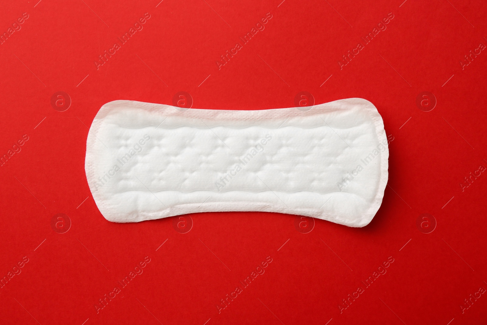 Photo of Menstrual pad on red background, top view