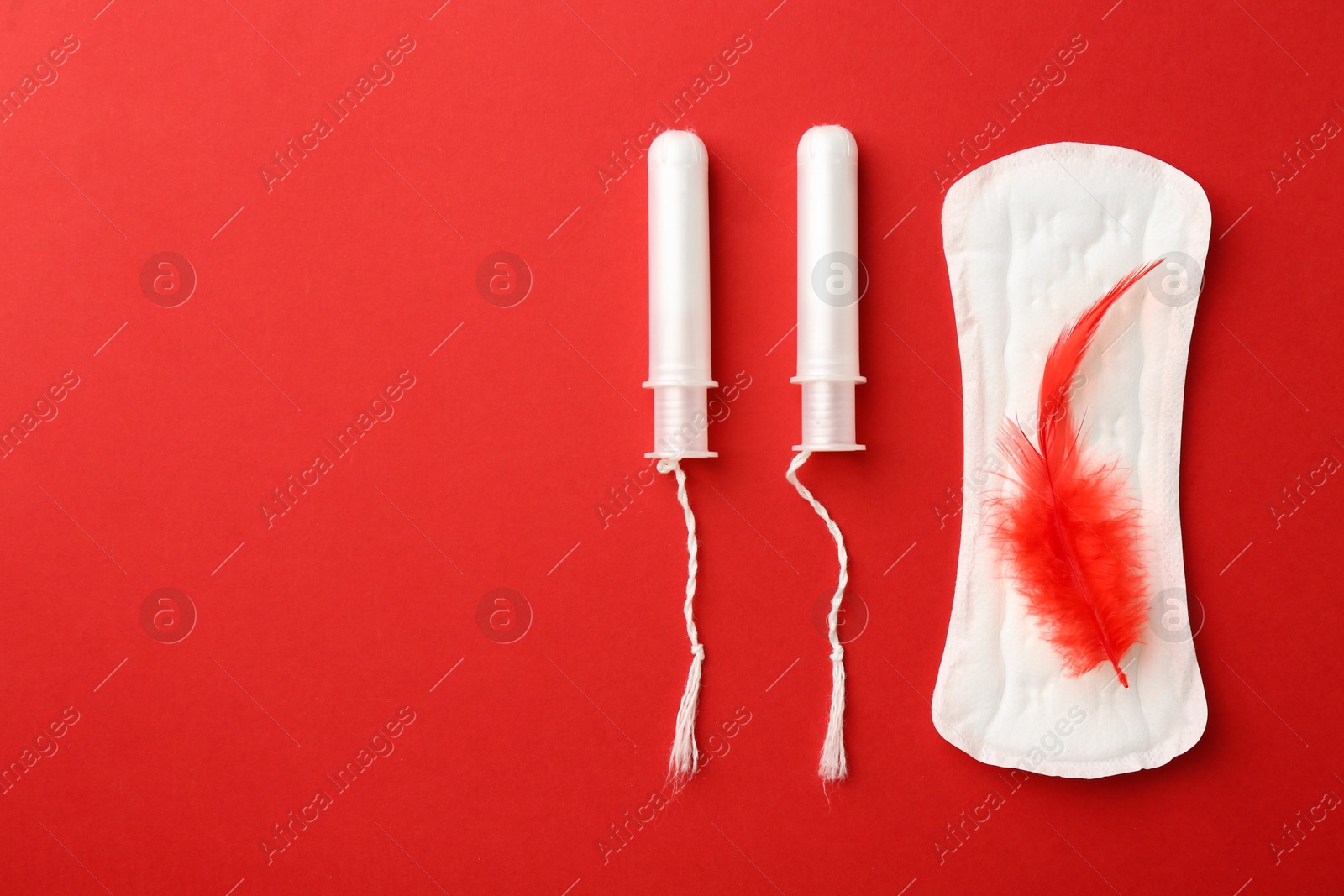 Photo of Menstrual pad and tampons on red background, top view. Space for text