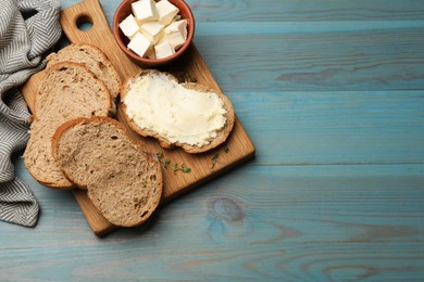 Photo of Fresh bread with butter on blue wooden table, flat lay. Space for text