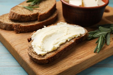 Photo of Fresh bread with butter and rosemary on blue wooden table, closeup