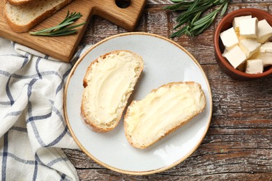 Photo of Fresh bread with butter and rosemary on wooden table, flat lay