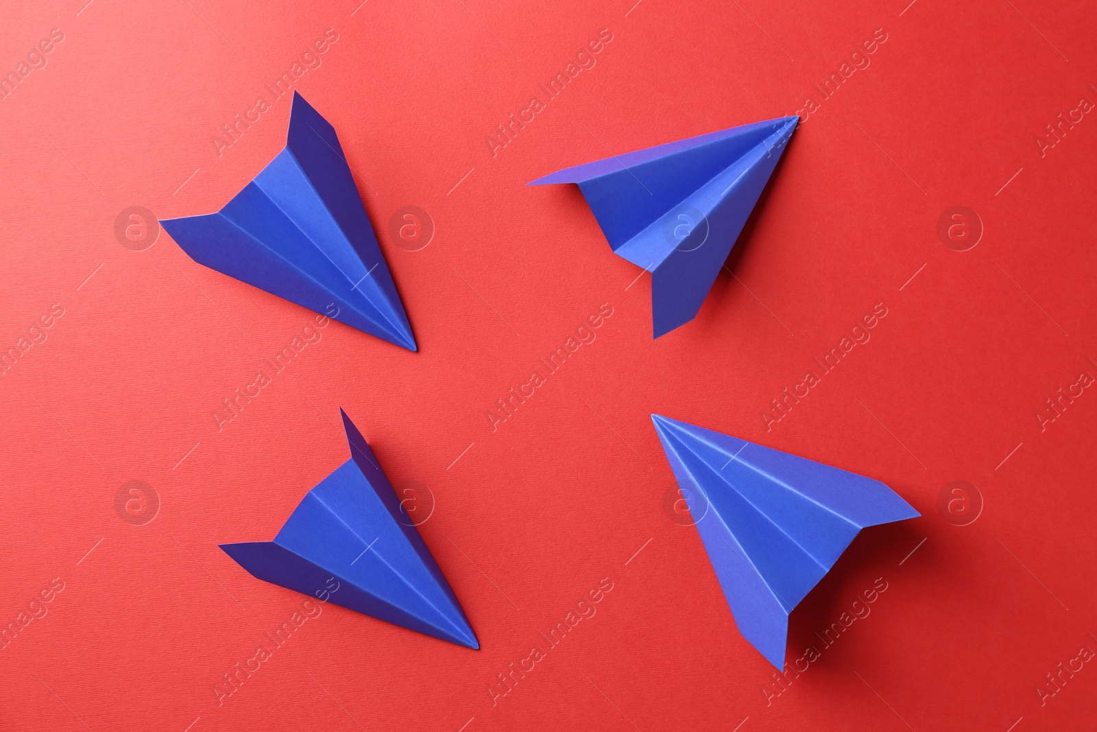 Photo of Blue paper planes on red background, top view