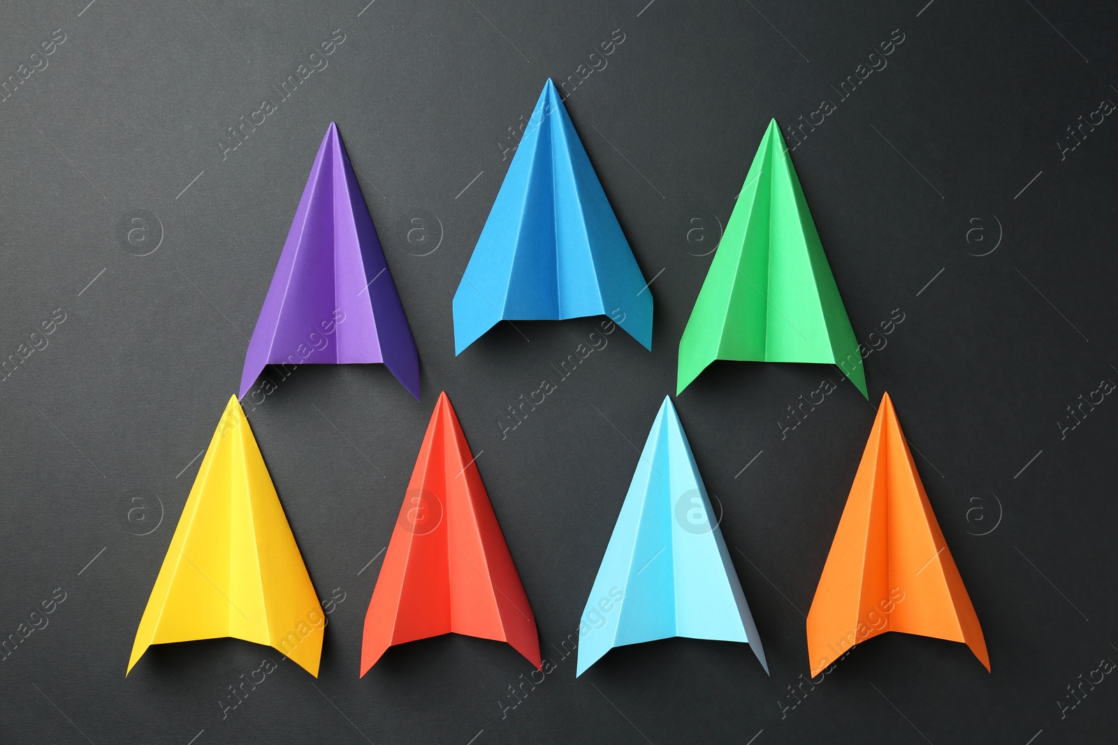 Photo of Colorful paper planes on black background, top view