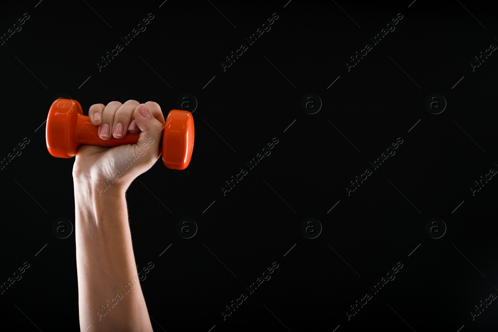 Photo of Woman exercising with dumbbell on black background, closeup. Space for text