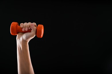 Photo of Woman exercising with dumbbell on black background, closeup. Space for text