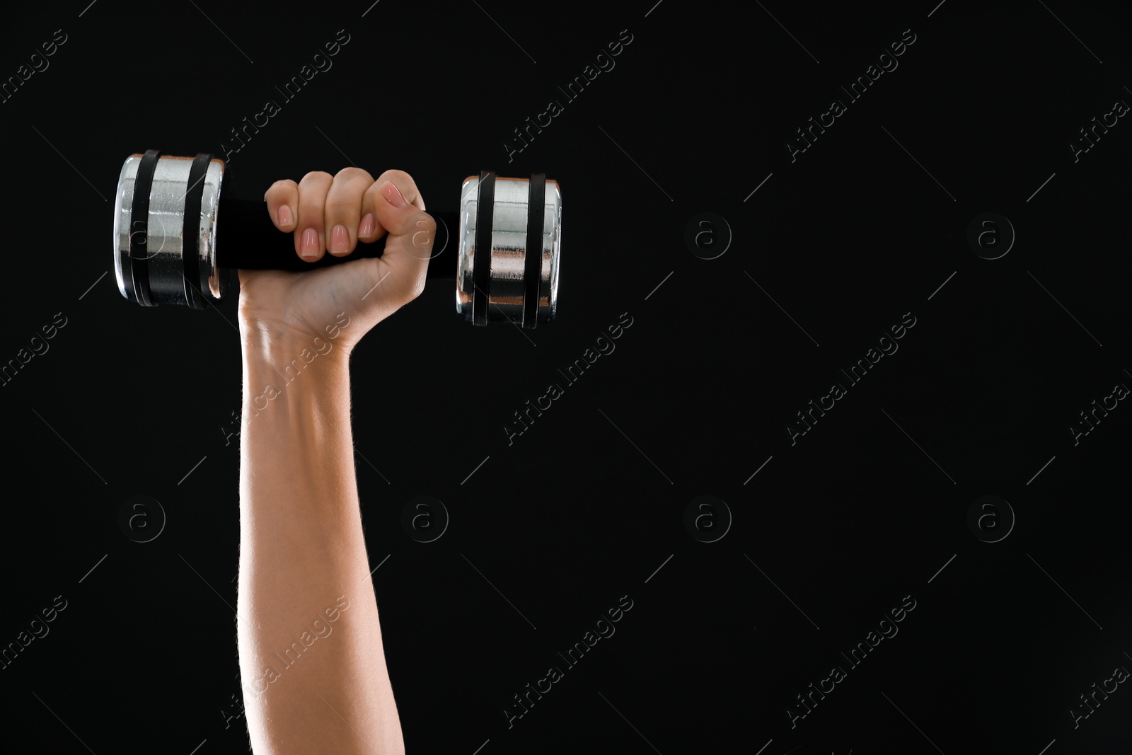 Photo of Woman exercising with dumbbell on black background, closeup. Space for text