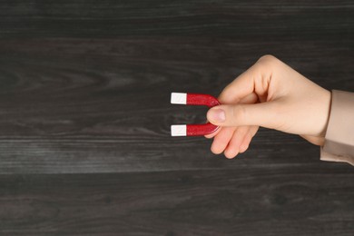 Photo of Woman with horseshoe magnet on wooden background, closeup. Space for text