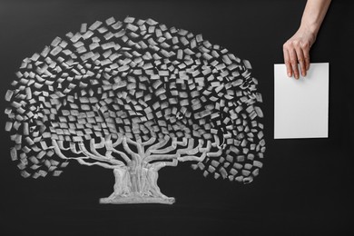 Photo of Woman holding blank paper sheet over chalkboard with tree drawing, closeup