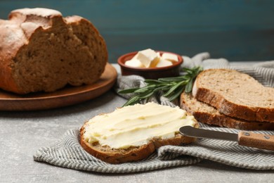 Photo of Fresh bread with butter and knife on grey table, closeup
