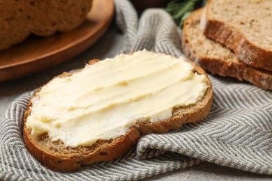 Photo of Fresh bread with butter on grey table, closeup