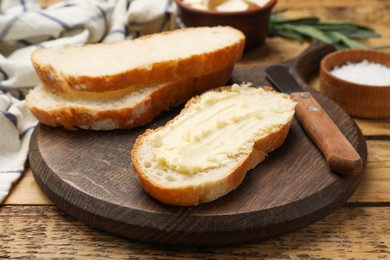 Photo of Fresh bread with butter and knife on wooden table, closeup