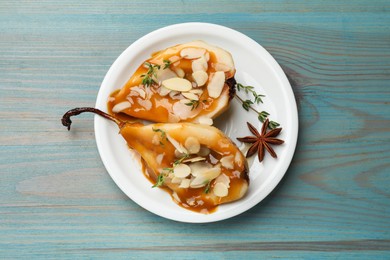 Photo of Delicious pears with caramel sauce, almond flakes and spices on blue wooden table, top view