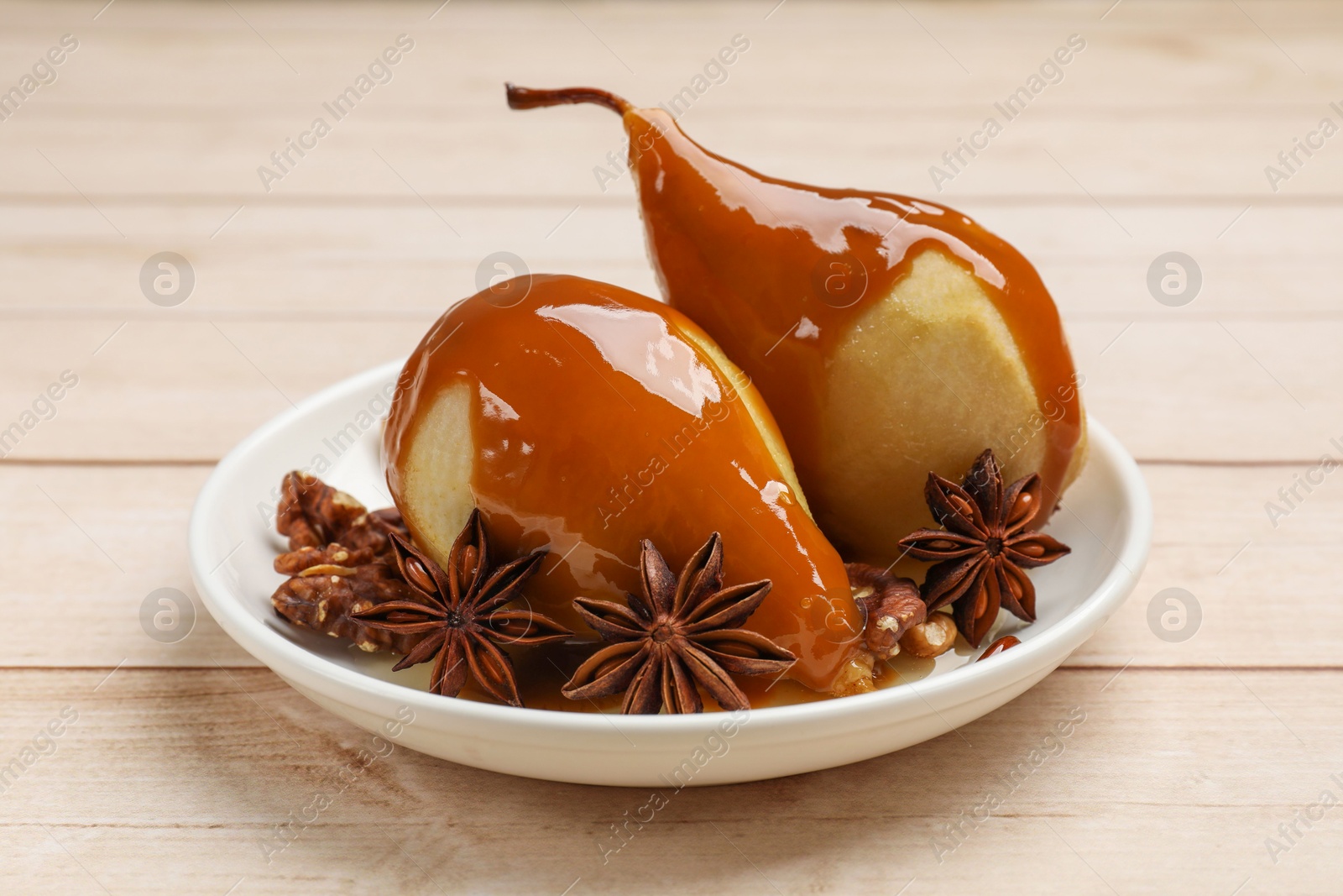 Photo of Delicious pears with caramel sauce and spices on white wooden table, closeup