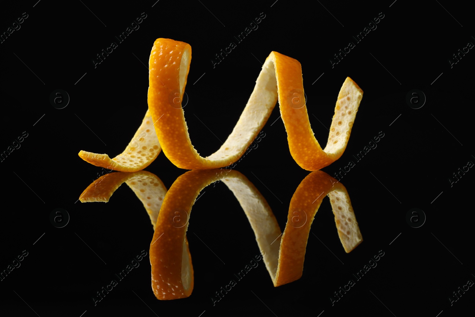 Photo of One fresh orange peel on black mirror surface