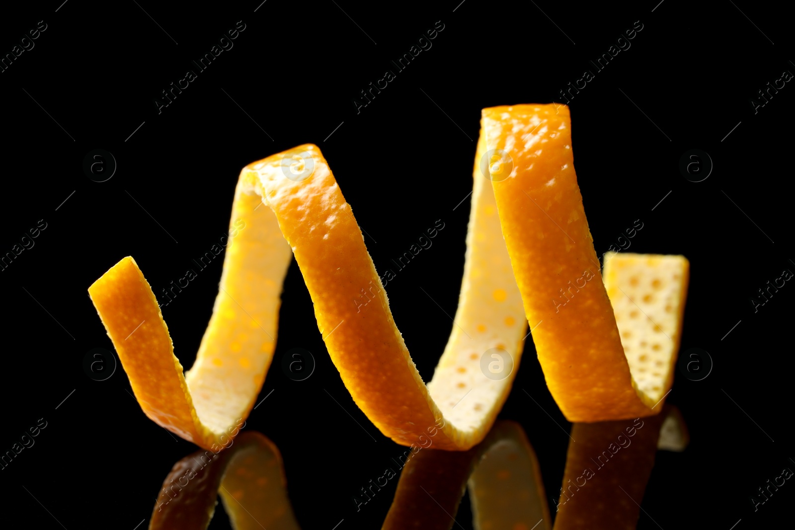 Photo of One fresh orange peel on black mirror surface, closeup