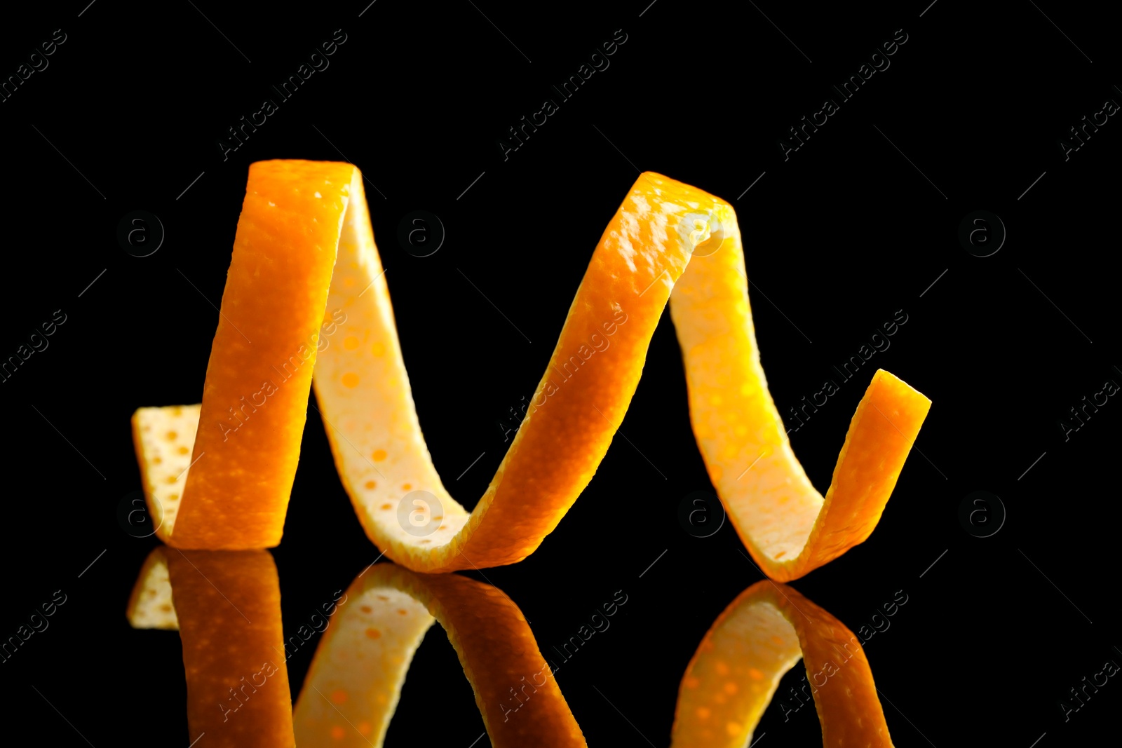 Photo of One fresh orange peel on black mirror surface, closeup