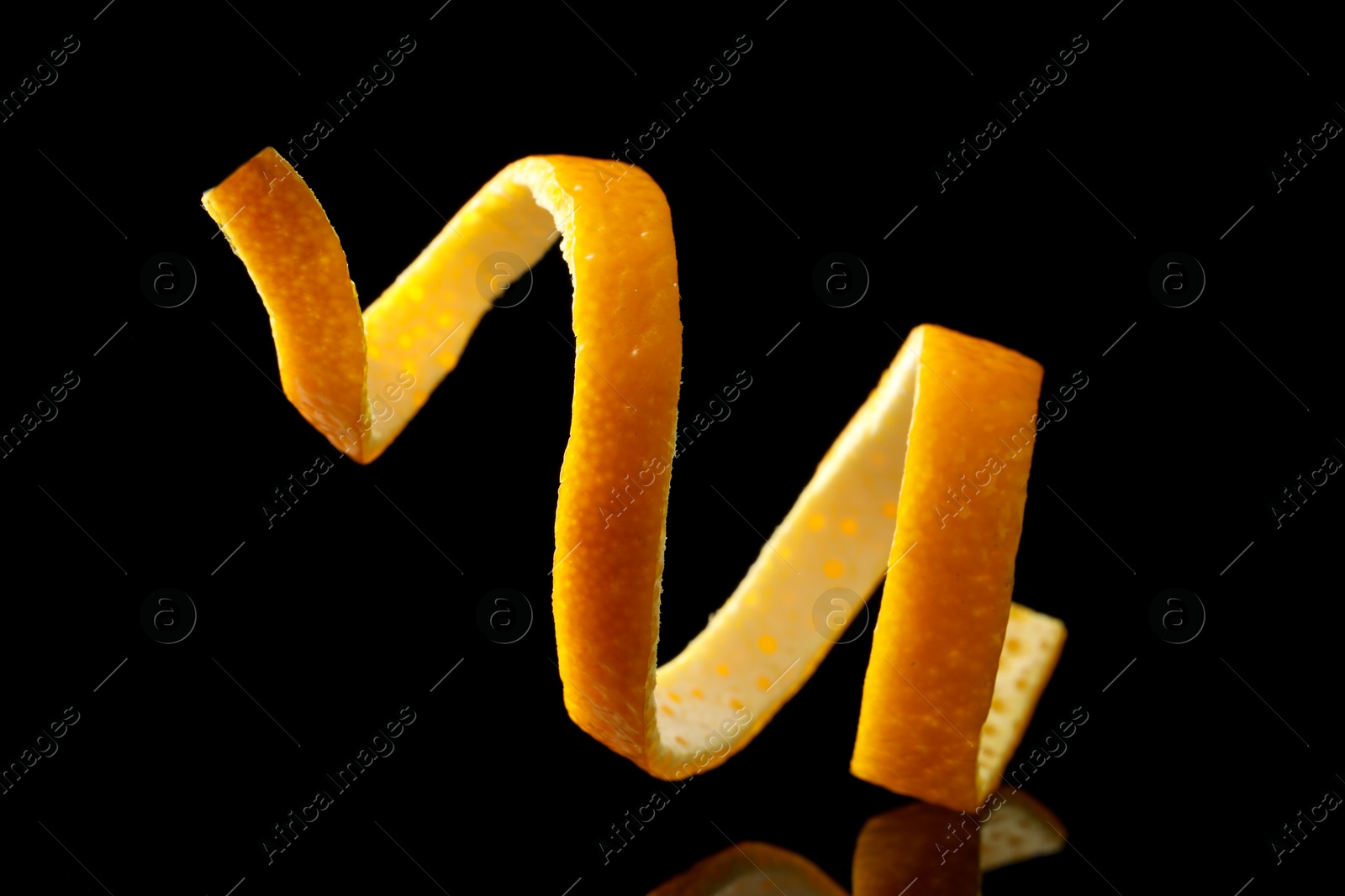 Photo of One fresh orange peel on black mirror surface, closeup