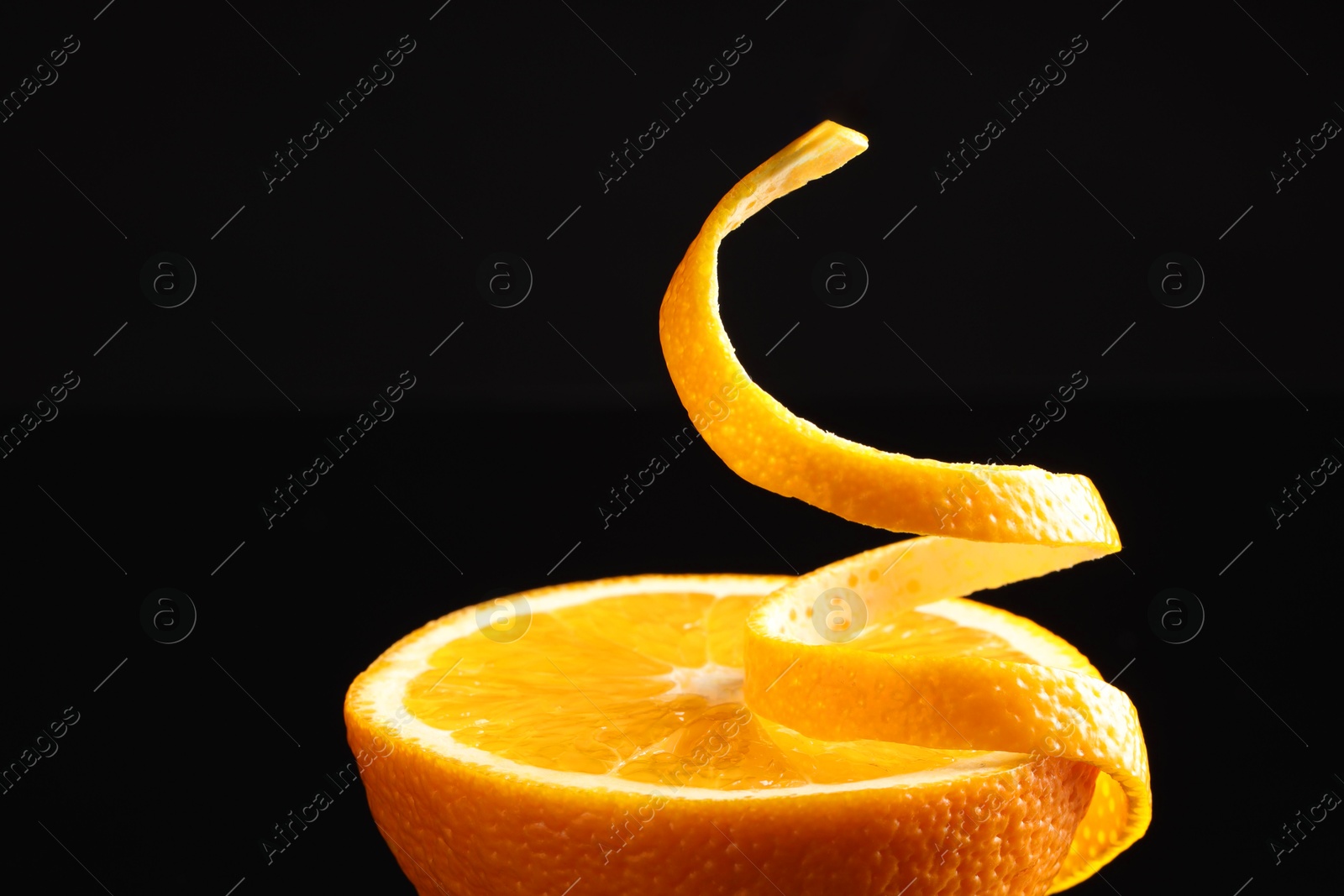 Photo of Fresh orange peel and half of fruit on black background, closeup