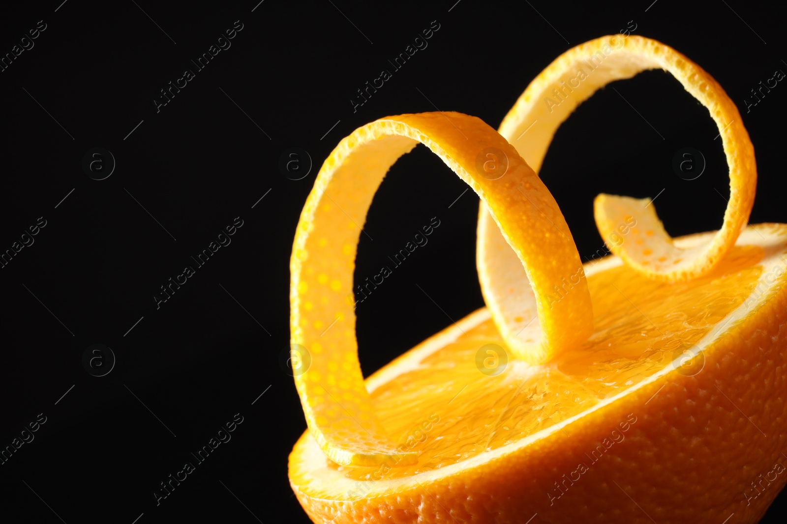 Photo of Fresh orange peel and half of fruit on black background, closeup. Space for text