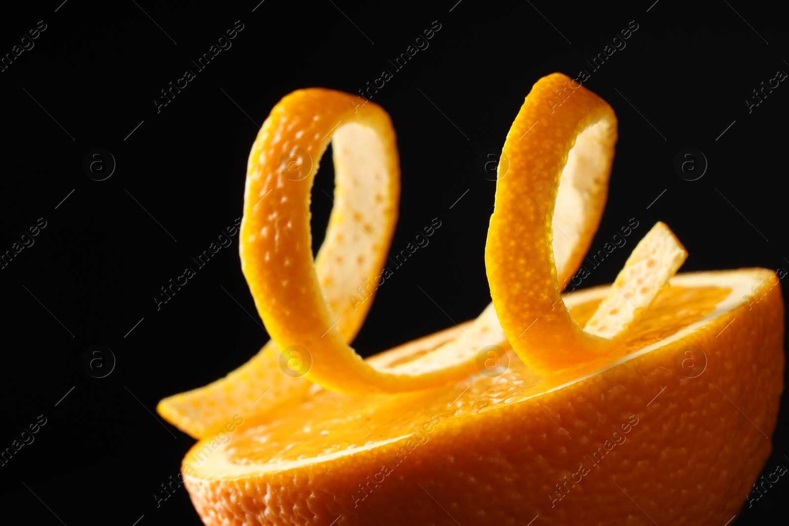 Photo of Fresh orange peel and half of fruit on black background, closeup