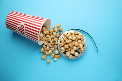 Photo of Sweet popcorn and film reel on light blue background, top view. Watching movie