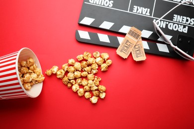 Photo of Movie clapper, sweet popcorn and tickets on red background, flat lay