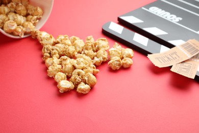 Photo of Movie clapper, sweet popcorn and tickets on red background, closeup