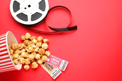 Photo of Sweet popcorn, movie tickets and film reel on red background, flat lay