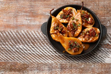 Photo of Delicious pears with caramel sauce, pecan nuts and thyme on wooden table, top view. Space for text