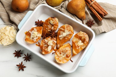 Photo of Delicious pears with caramel sauce, almond flakes and spices on white marble table, flat lay